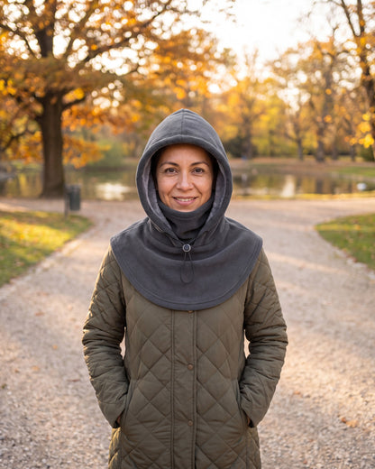 Woman in a park wearing a dark gray fleece balaclava hood with the face cover folded down
