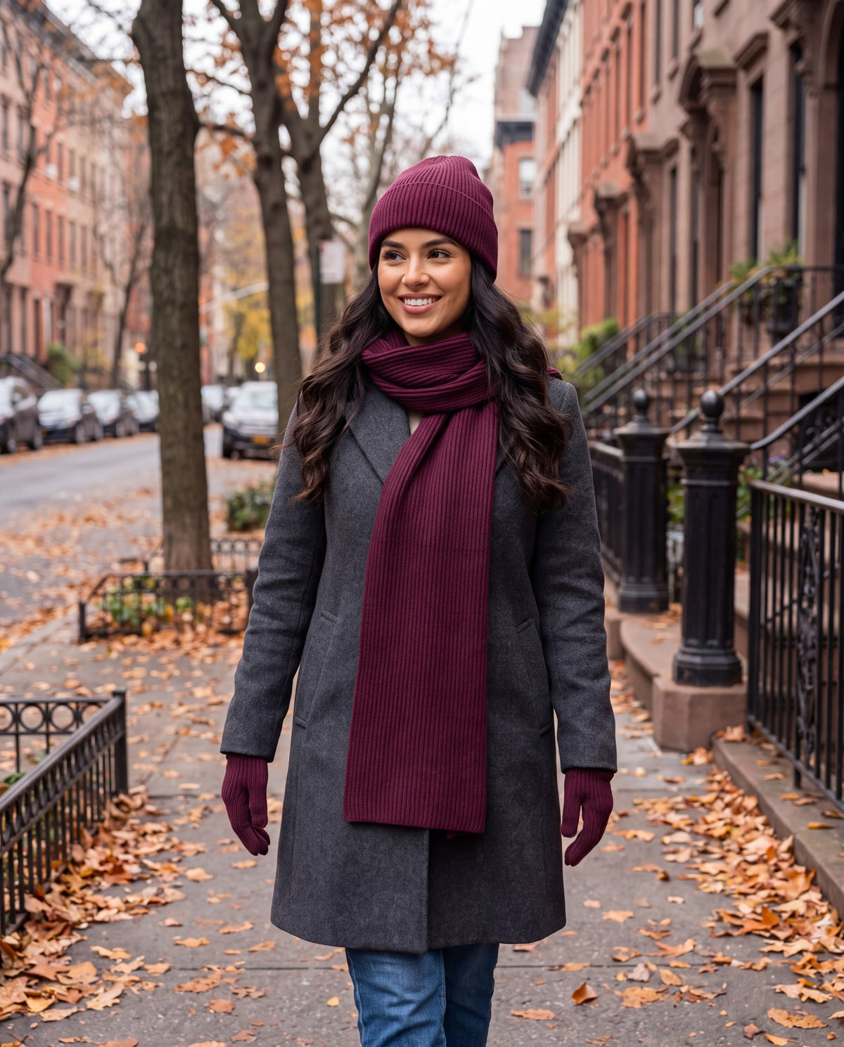 Burgundy rib knit beanie, scarf and gloves set worn by a woman on a city street