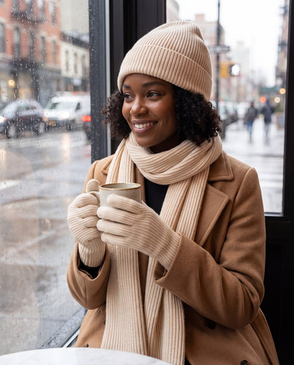 Cream rib knit beanie, scarf and gloves set worn by a woman in a cafe
