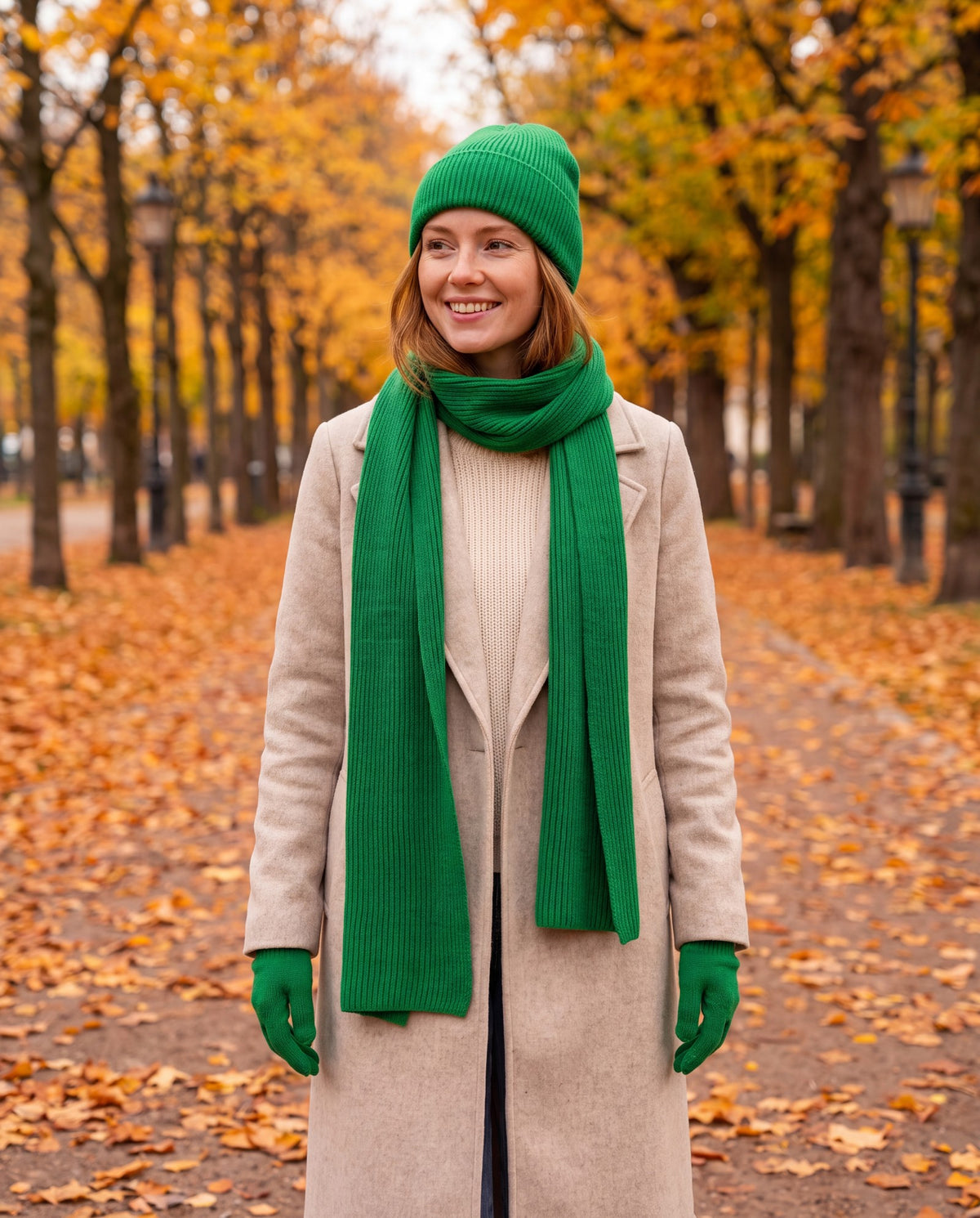 Green rib knit beanie, scarf and gloves set worn by a woman in a park