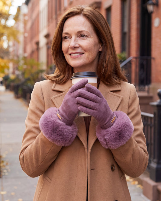 Woman wearing purple faux fur cuff gloves holding a coffee on a city street