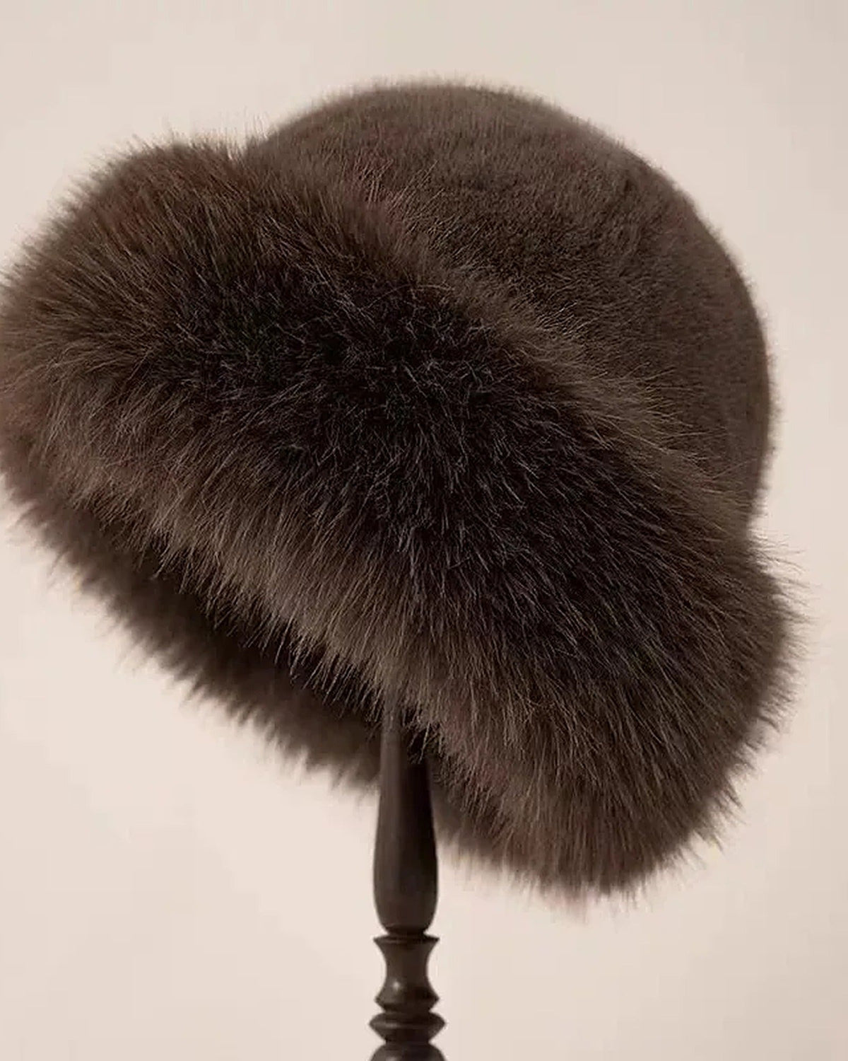 Brown faux fur hat with rolled brim on a hat stand
