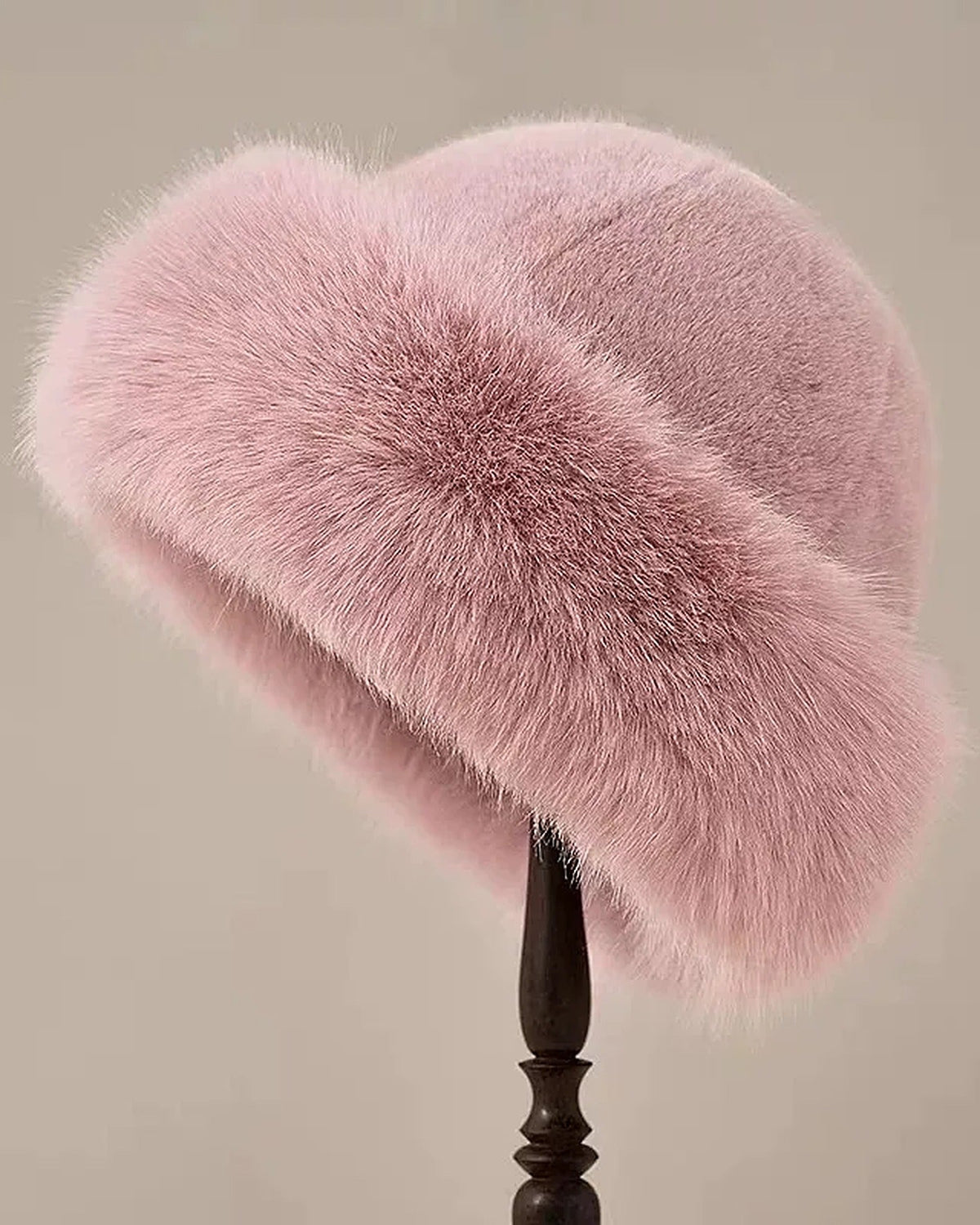 Pink faux fur hat with rolled brim on a hat stand