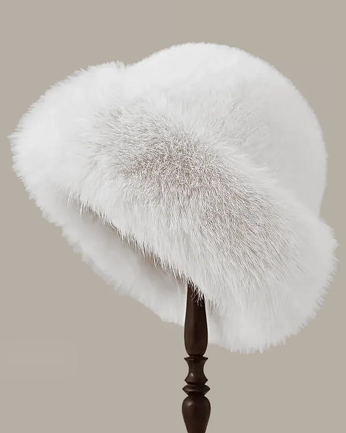 White faux fur hat with rolled brim on a hat stand