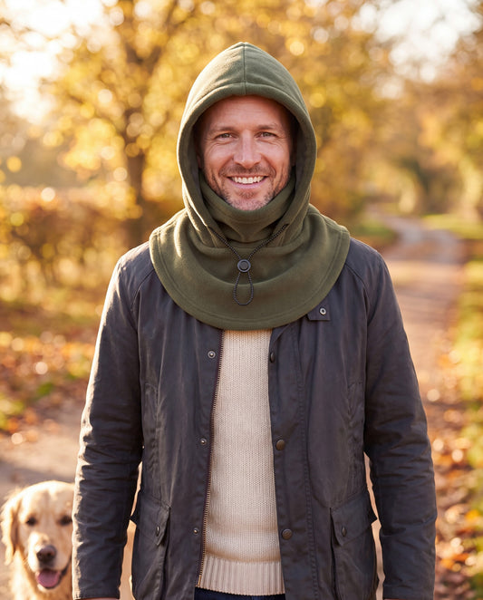 Man on a footpath with his dog wearing an army green fleece hood with the face cover folded down