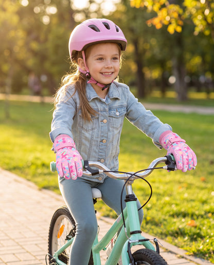 Girl riding a bike in a park wearing pink printed kids waterproof gloves