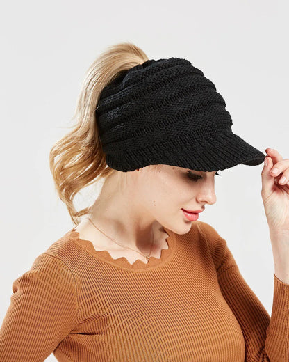 Woman wearing a black ponytail beanie with brim and her ponytail through the back