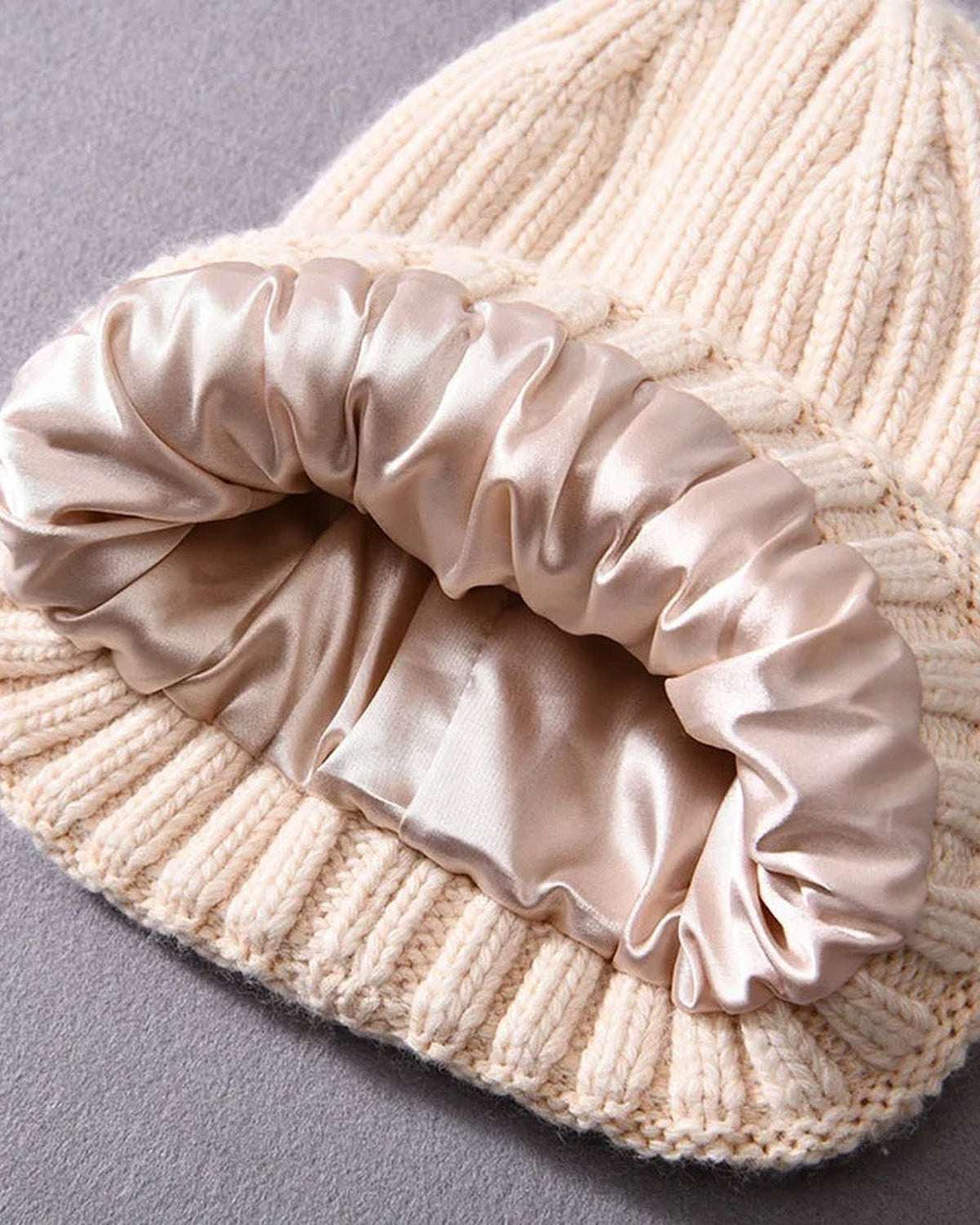 Inside of a cream satin-lined beanie showing the smooth satin lining
