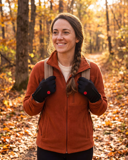 Woman hiking a forest trail holding her backpack straps in black thermal touchscreen gloves with zip cuffs